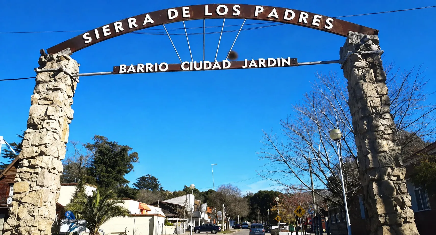 El arco de piedra de la entrada, con el nombre del lugar en letras de chapa sobre la avenida